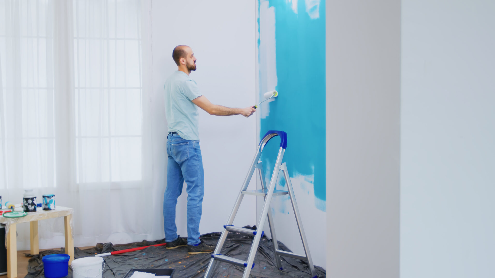 Peintre professionnel appliquant de la peinture intérieure au rouleau sur un mur
