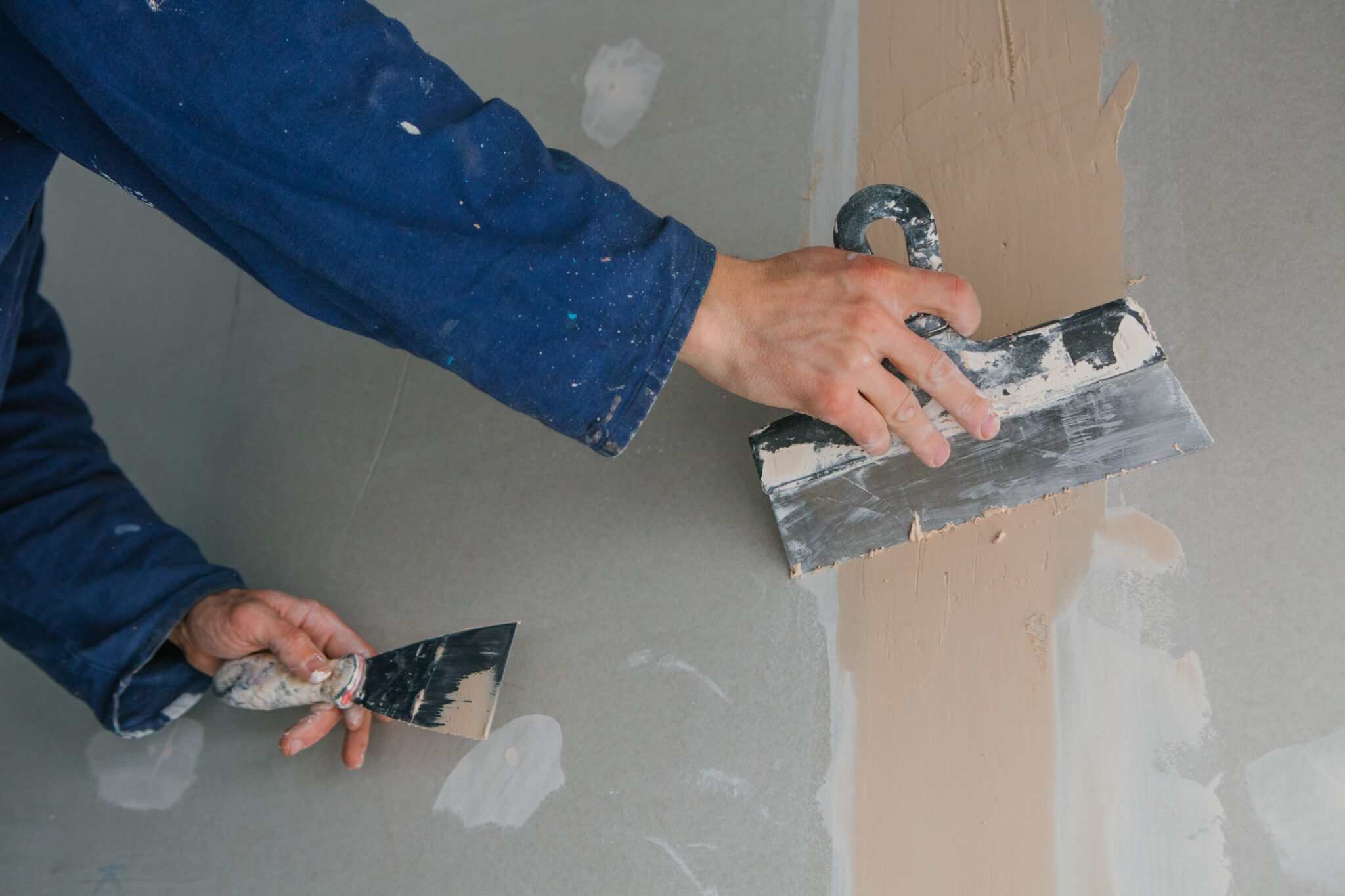 Artisan plaquiste appliquant un enduit pour bande à placo sur plaque de plâtre